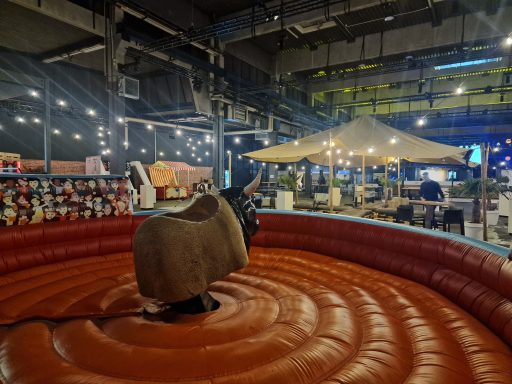 Ein mechanischer Bulle auf einer roten Arena in einem festlichen Indoor-Bereich.