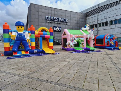 Bunte Hüpfburgen, darunter ein Lego-Figur und zwei themenbezogene Spielburgen.