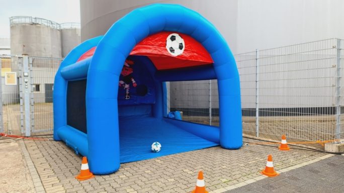 Blaues aufblasbares Fußballtor mit einem Ball und Sicherheitskonen um die Umgebung.