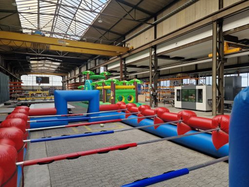 Bunte Hüpfburg-Landschaft in einer Industriehalle mit mehreren Attraktionen.