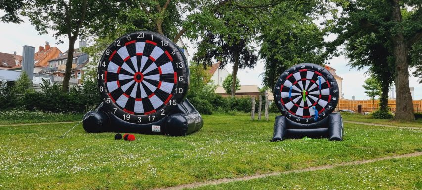 Zwei große, aufblasbare Dartscheiben auf einer Wiese.