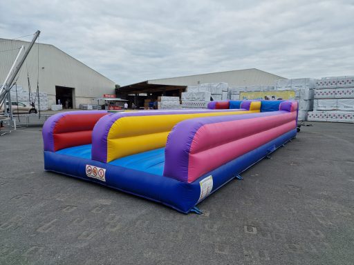 Buntes, aufblasbares Spielgerät mit mehreren Zonen in Rot, Gelb, Pink und Blau.