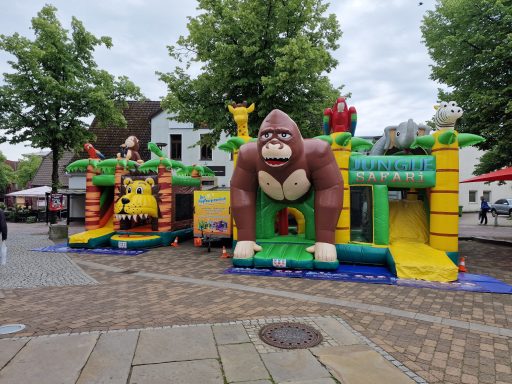 Aufblasbare Hüpfburgen in Form eines Gorillas und eines Löwen auf einem Platz.