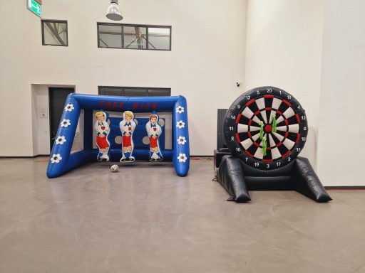 Aufblasbare Dartscheibe und Fußballspiel auf einem Hallenboden.