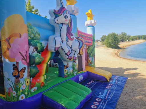 Luftspielplatz mit einem Einhorn, bunten Blumen und einer sandigen Uferlandschaft.