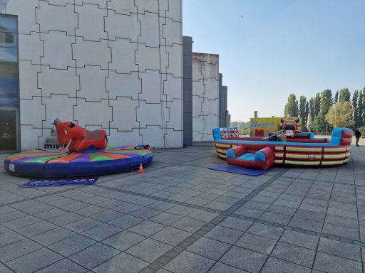 Luftgeblasenes Spielzeug: ein mechanisches Pferd und eine bunte Hüpfburg im Freien.