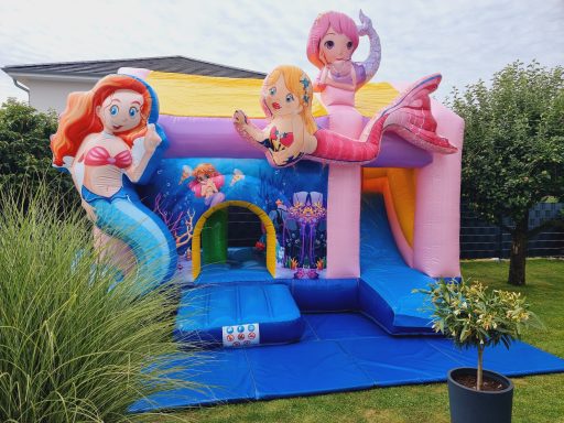 Bunte Hüpfburg mit Meerjungfrauen und einem Wassermotiv im Freien.