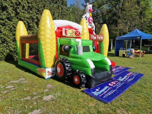 Bunte Hüpfburg in Form eines Traktors mit Maiskolben und einer aufgestellten Figur.