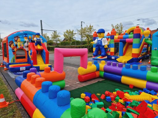 Bunte Hüpfburg mit Rutschen und Spielgeräten für Kinder im Freien.