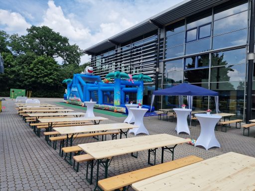 Buntes Spielenetz mit Festtischen im Freien und einem Pavillon.