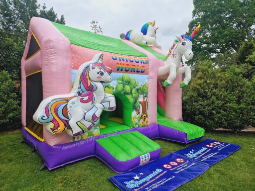 Buntes Einhorn-Hüpfburg mit zwei Einhörnern und Zugangsrampe im Garten.