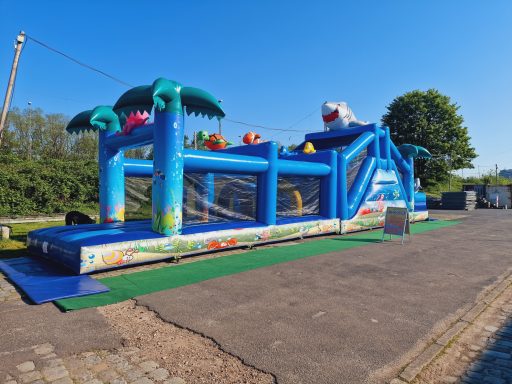 Buntes Hüpfburg mit Palmen und Rutsche, auf einem sonnigen Platz.