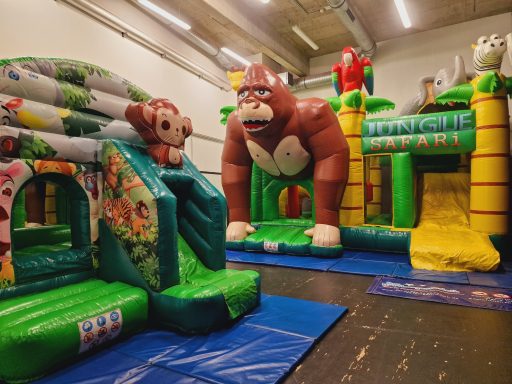 Aufblasbare Spielgeräte mit einem großen Affen und einer Rutsche in einer Halle.