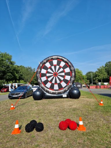 Großes aufblasbares Dartscheibe im Freien mit roten und schwarzen Darts.