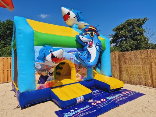 Bunte Hüpfburg mit Meerestieren, darunter Haie, vor einem klaren blauen Himmel.