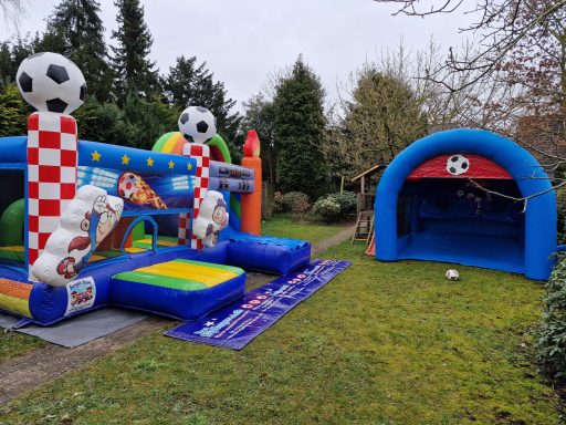 Luftige Hüpfburg mit Fußballmotiv und Spielfeld in einem Garten.