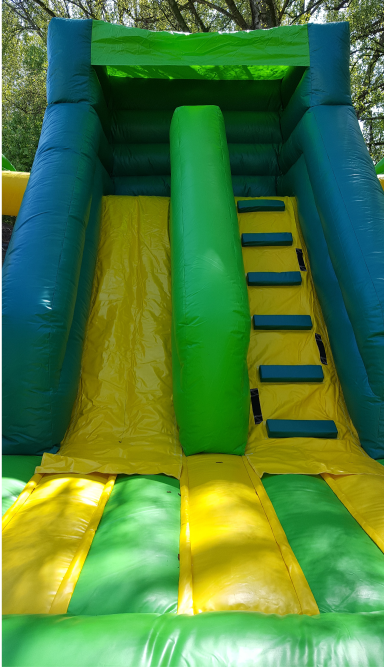 Bunte Rutsche mit grüner Treppe und Kletterbereich in einem Spielplatz.