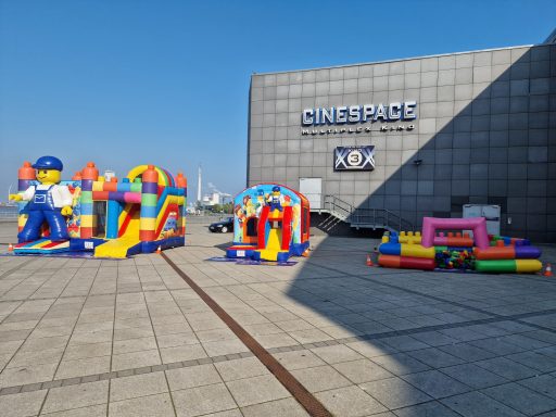 Bunte Hüpfburgen auf einem Platz vor einem modernen Gebäude.