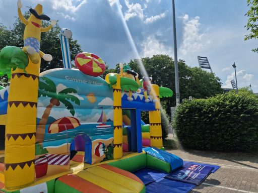 Bouncy castle mit Strandmotiv, Sonnenschirm und bunten Luftballons im Freien.