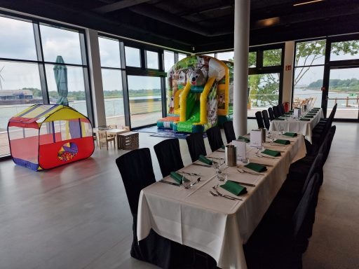 Ein Restaurant mit gedecktem Tisch, einer Hüpfburg und einem Spielzelt im Hintergrund.