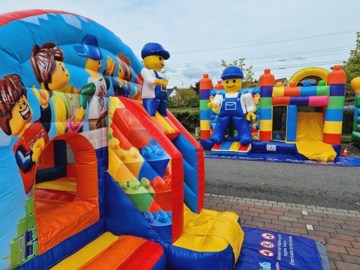 Bunte Hüpfburg mit LEGO-Figuren und verschiedenen Rutschen und Spielbereichen.