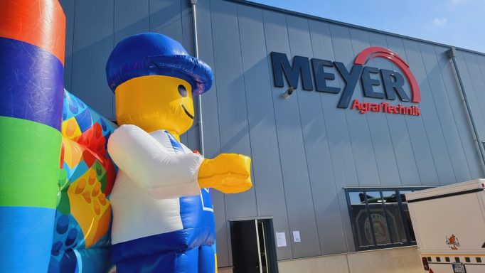 Bunte LEGO-Figur mit blauer Mütze steht vor dem Gebäude von Meyer Sport.