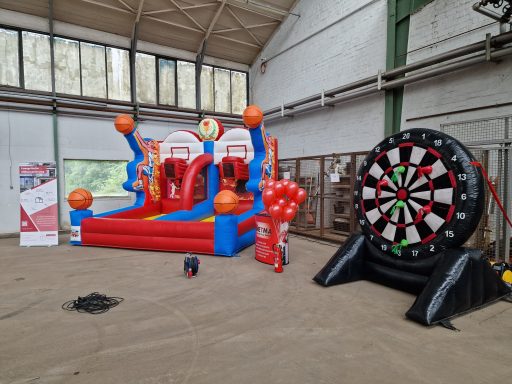 Luftballon-Spielplatz mit Basketball-Korb und Dartbrett in einer Halle.