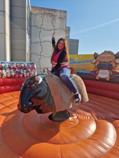 Frau reitet auf einem mechanischen Bullen in einem Festzelt im Freien.