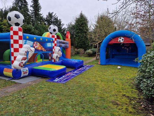 Bunte Hüpfburg mit Fußballmotiven und aufblasbarem Tor im Garten.