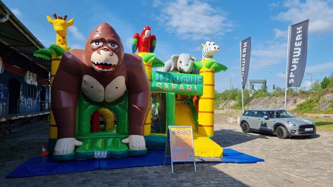 Buntes Hüpfburgen-Spielgerät mit einem großen Affen und weiteren Tieren im Freien.